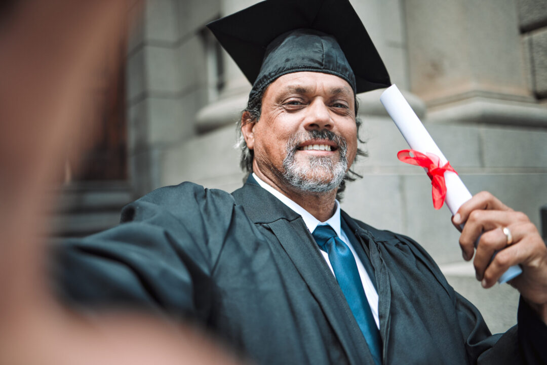 Mature graduate smiling in graduation attire
