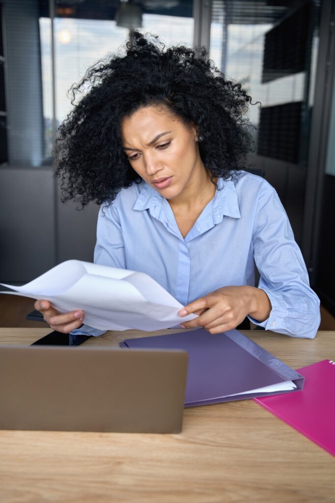Concerned African American businesswoman doing paperwork reading report.