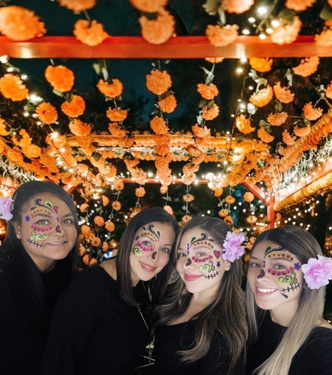 The law office team with calavera face paint under marigolds at a Dia de los Muertos celebration