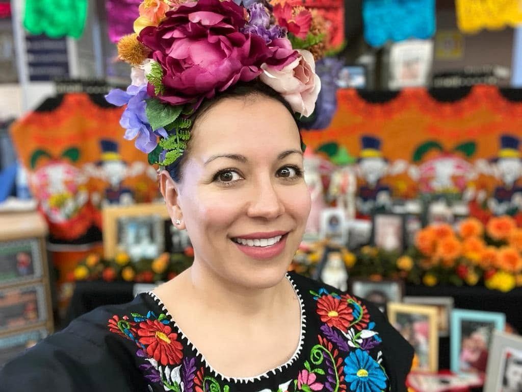 Gilda McDowell in a flower crown beside a Dia de los Muertos altar