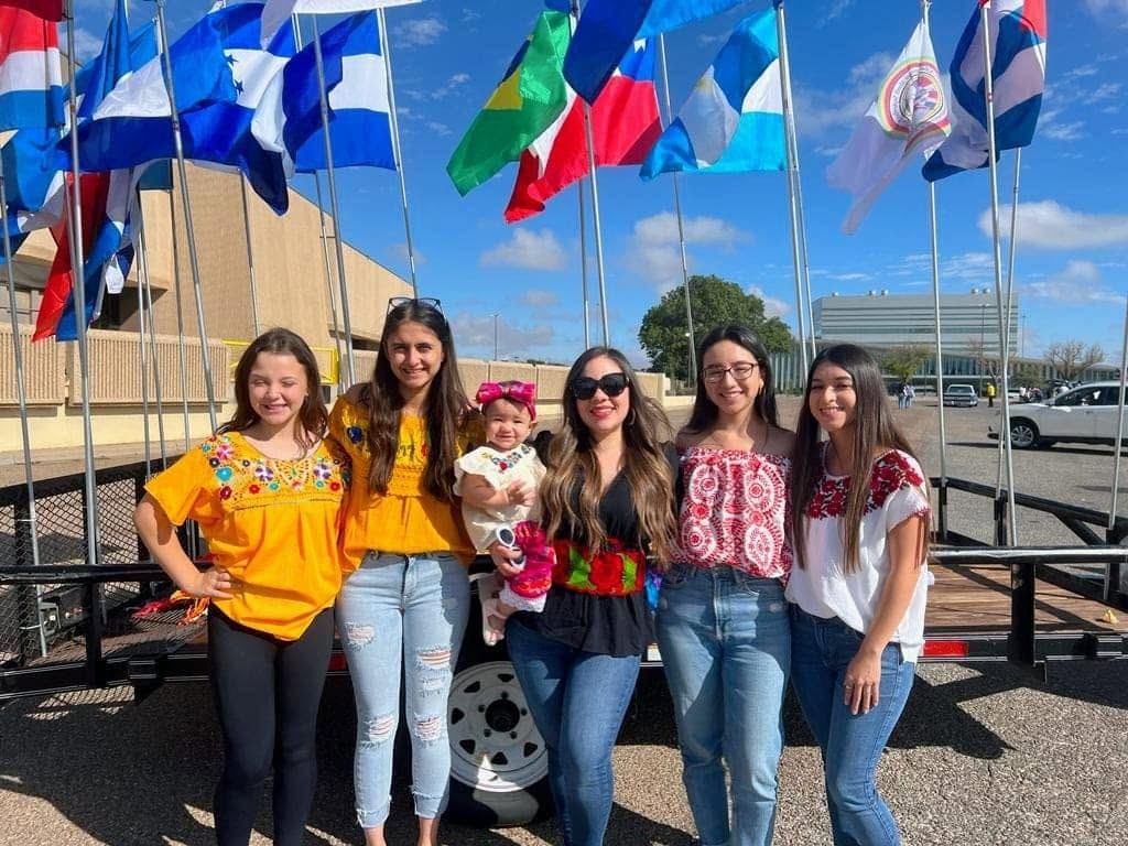 The Gilda McDowell team standing under the flags of Latin American countries at a community event in Lubbock